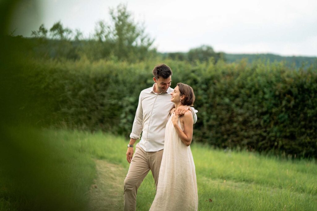 Brautpaar schaut sich lächelnd an beim Spaziergang im Grünen in Sinzig – natürliche Hochzeitsfotografie NRW